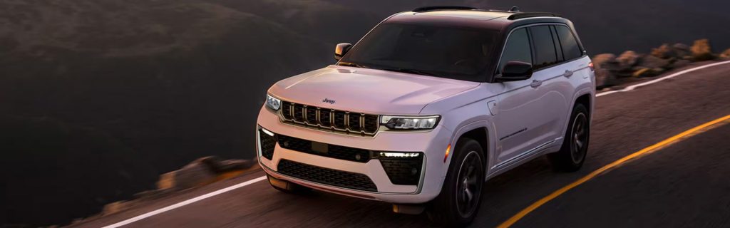 2026 Jeep Grand Cherokee driving on a scenic mountain road. 
