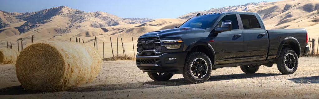 2026 RAM 2500 truck in black, driving through a rural landscape